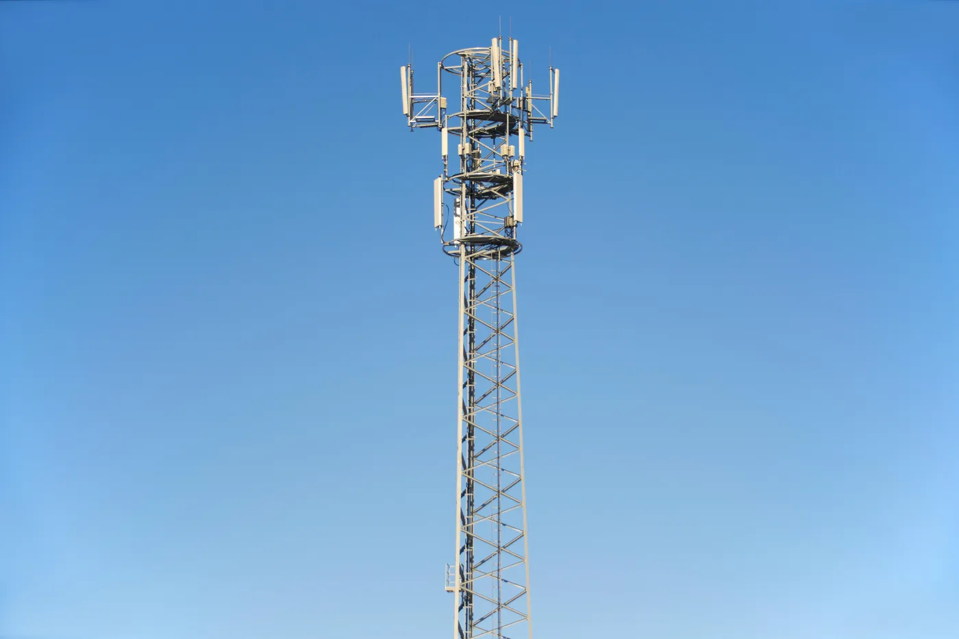 Steel lattice telecommunications tower with antenna equipment against a clear blue sky